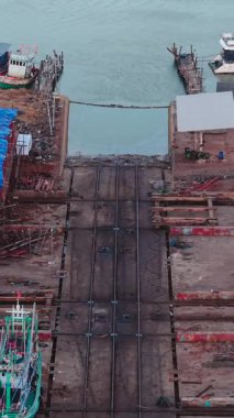 Büyük nehir boyunca balıkçı teknelerinin onarıldığı tersanenin havadan görünüşü FullHD Dikey