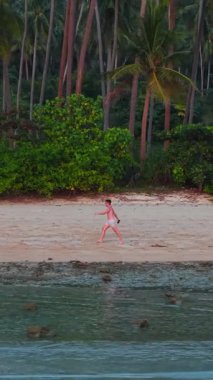 Gün batımında güzel bir sahilde yürüyen genç adam denizden gelen FullHD dikey İHA ile filme alındı.