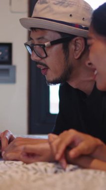 Genç Asyalı çift internette dizüstü bilgisayar kullanıyor ve FullHD dikey film izliyor.