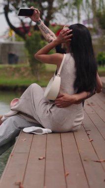 Şehir parkında, FullHD Dikey Liman 'da gölde selfie çeken genç bir çift.