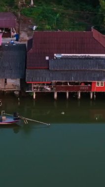 Geleneksel Tayland stilt evleri insansız hava aracı bakış açısından sakin bir nehir hizasında.