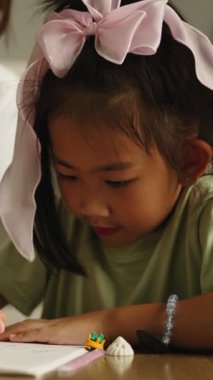 Asyalı bir anne genç kızına ödevlerinde yardım eder ve pozitif bir öğrenme deneyimini teşvik eder.