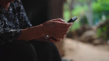 Yaşlı bir Senatda kadınının elleri akıllı telefon tutuyor ve kullanıyor - 4K Yatay