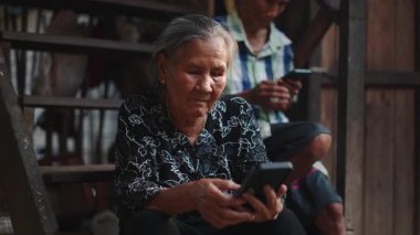 Üst düzey bir kadın merdivenlerde oturan ve arka planda telefon kullanan bir adamla oturuyor - 4K Yatay