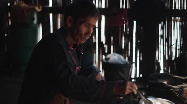 Yaşlı bir lahu kadını kırsal bir mutfakta geleneksel yöntemlerle yemek hazırlıyor - 4K Yatay