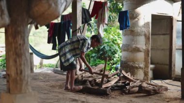 Lahu 'lu bir adam kırsal bir köyde verandanın altında yakacak odun kesiyor - 4K Yatay
