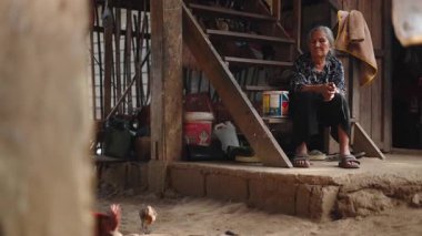 Sundurmasının merdivenlerinde dinlenen yaşlı kadın sakince tavukları besliyor - 4K Yatay