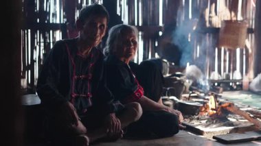 Lahu kabilesinden yaşlı bir çift yakacak odunla yemek pişirirken yerde oturuyor - 4K Yatay