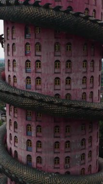 Wat Samphran bir Budist tapınağı etrafında kocaman yeşil bir ejderha olan eşsiz bir pembe silindirik bina sergiler.