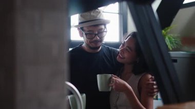 Genç çift birlikte sakin bir sabahın tadını çıkarıyor kahve içip gülüyorlar - 4K Yatay