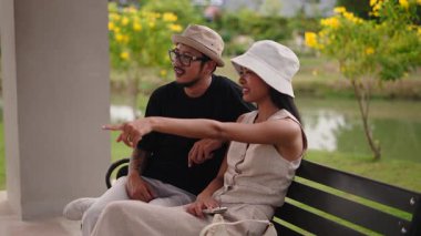 Bir bankta oturan turistler tatillerinin tadını çıkarıyorlar ve sessizce sohbet ediyorlar - 4K Yatay