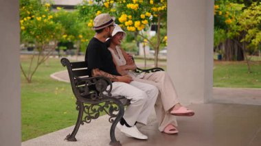 Genç Taylandlı çift parkta bir bankta rahatça eğleniyor - 4K Yatay