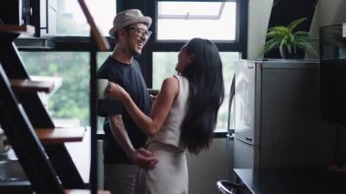 Genç Asyalı çift mutfakta dans edip eğlenirken kahvenin tadını çıkarıyor - 4K Yatay