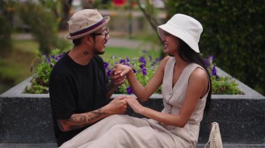 Taylandlı romantik çift dışarıda bir bankta flört ediyor ve eğleniyorlar - 4K Yatay