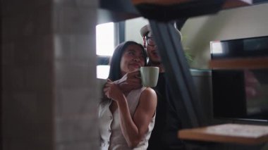 Genç Asyalı çift gülüyor ve birlikte kahve içiyorlar. Çatı katında - 4K Yatay