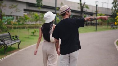 Parkta el ele tutuşan iki Asyalı turist - 4K Yatay