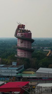 Tayland 'daki Wat Samphran tapınağı etkileyici kulesinin bulutlu gökyüzünde bir ejderhayla iç içe olduğunu gösteriyor.