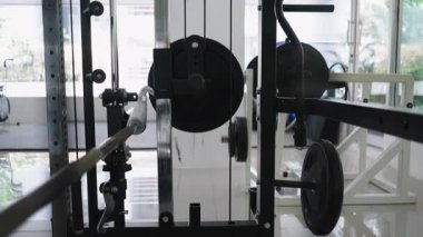 Ağırlıkların yanındaki spor aletlerinin yakın görüntüsü ve parlak bir spor salonunda dönen kablolar - 4K Yatay