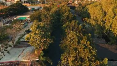 Tropikal bir ortamda ağaçlarla çevrili bir toplulukta süzülen sakin bir kanal - 4K Yatay