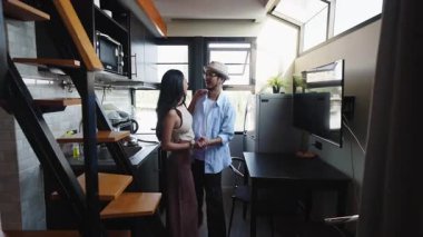 Küçük modern evlerinin mutfağında şapka takan mutlu Asyalı çift - 4K Yatay