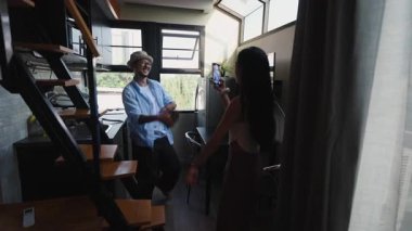 Genç bir kadın mutfakta akıllı bir telefonla dans eden bir adamı filme alıyor - 4K Yatay