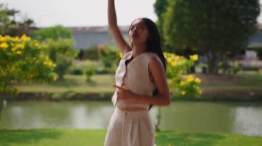 Kaygısız uzun saçlı Asyalı genç kadın parkta serbest dans ediyor - 4K Yatay