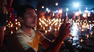 Latin çocuk Bangkok 'taki Fener Festivali' nde 4K Horizontal 'da video kaydederken akıllı telefonunu elinde tutuyor.