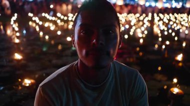 Genç Latin adam fener festivalinde yüzlerce mumla çevrili kameraya bakıyor - 4K Yatay