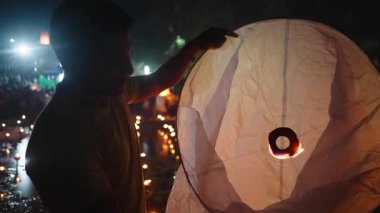 Genç Latin adam fener yangınının yardımıyla gökyüzüne yükselmek için büyük kağıt fenerler hazırlıyor - 4K Yatay