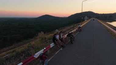 Motorcular dağ yolunda mola verip güzel bir günbatımı manzarasının tadını çıkarıyorlar - 4K Yatay