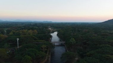 Gün batımında sık bir ormanın içinden süzülen sakin nehir - 4K Yatay