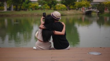 Romantik bir çift gölün kenarında sakin bir anın tadını çıkartıyor - 4K Yatay