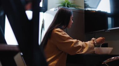 Genç Asyalı kadın mutfak masasında sağlıklı vejetaryen salatasının tadını çıkarıyor - 4K Yatay