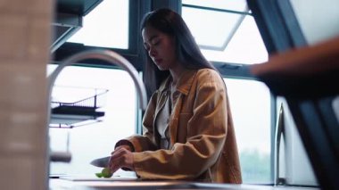 Genç Asyalı kadın dikkatlice bir mutfakta ahşap bir kesme tahtasına limon kesiyor - 4K Yatay