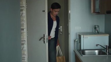 Market poşetleri taşıyan genç adam yiyecek alışverişi yaptıktan sonra mutfağa giriyor. Bağımsız Yaşam - 4K Yatay