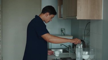 Su, mutfak tezgahının yanında duran genç bir Asyalı tarafından şeffaf bir fincana dökülüyor.