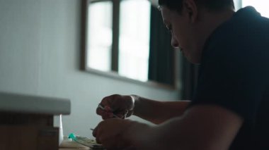 Genç adam mutfak masasında oturmuş taze salata yiyor ve kendini suyla suluyor - 4K Yatay