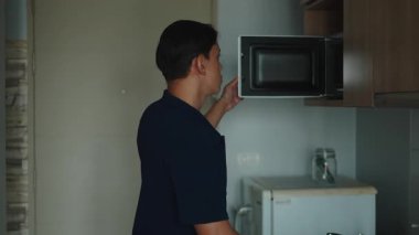 Modern Asyalı Genç Adam Mutfak Mikrodalgası İçinde Uygun Yiyecekleri Isıtıyor - 4K Yatay