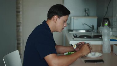 Yetişkin Adam, modern bir mutfakta haşlanmış yumurta ve taze sebzelere dayalı besleyici yemeğin tadını çıkarıyor - 4K Yatay