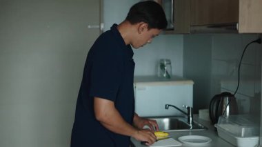 Genç adam sağlıklı bir yaşam tarzıyla minimalist ve temiz mutfak tezgahında olgun bir muzu dikkatlice soyuyordu - 4K Yatay