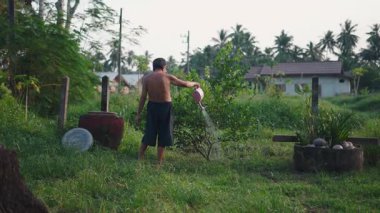 Tişörtsüz Asyalı yaşlı çiftçi sessiz bir bahçede bitkileriyle ilgileniyor - 4K Yatay