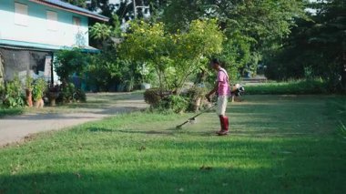 Ağır botlar giyen profesyonel bahçıvan çimleri biçme makinesiyle biçiyor - 4K Yatay