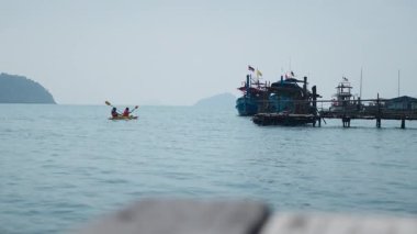 İki adam tahta iskelenin yanındaki kanoda kürek çekiyorlar - 4K Yatay