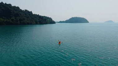 Kano, yemyeşil adaların yakınlarındaki sakin bir gölde seyir halinde - 4K Yatay