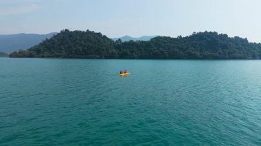 İHA, adanın yanındaki açık denizde iki kişi ile birlikte çift kano üzerinde uçuyor. 4K Yatay