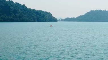 Bereketli yeşilliklerle çevrili sakin bir gölde kano - 4K Yatay