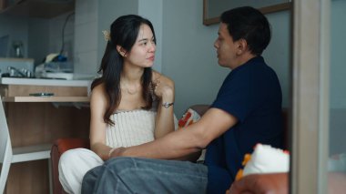 Asyalı çift evdeki kanepelerinde rahatça sohbet ediyorlar.