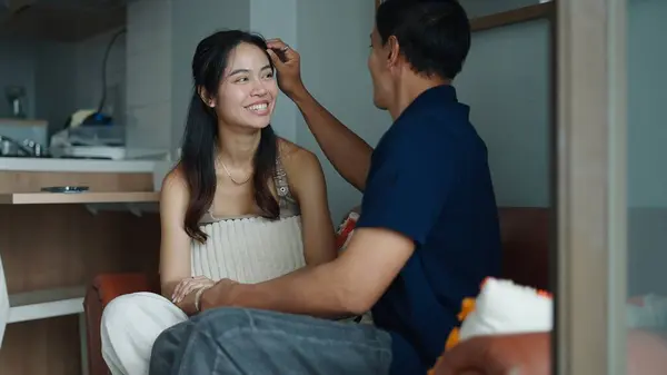 Sevgi dolu bir çift, kapalı mekanda samimi bir şekilde eşlerinin saçlarını okşuyor.