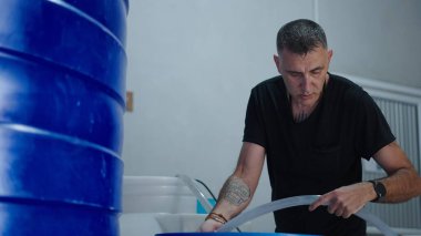 Kenevir yetiştiricisi besin seviyelerini kontrol ederken kapalı alanda kontrollü büyüyen çevrede hidroponik marihuana bitkileriyle ilgilenir.