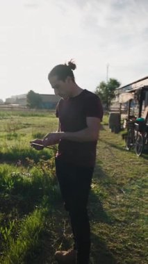 Elma ağaçları arasındaki dijital tablette gezinen genç çiftçi, tarımsal ilerlemeyi izliyor